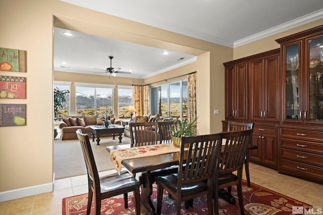 dining space with light tile patterned floors, ornamental molding, a ceiling fan, baseboards, and a mountain view