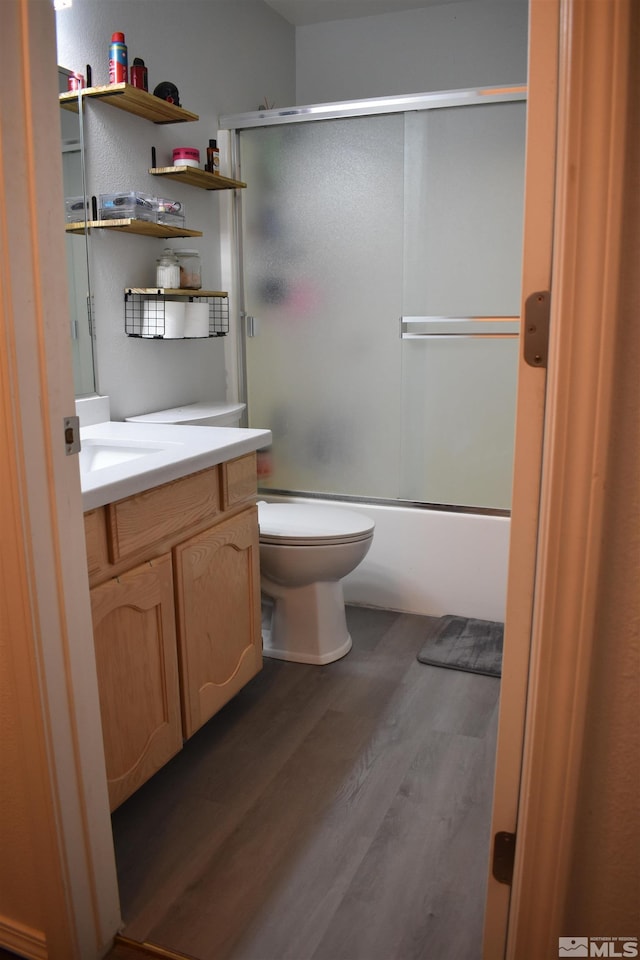 full bath with wood finished floors, vanity, toilet, and enclosed tub / shower combo