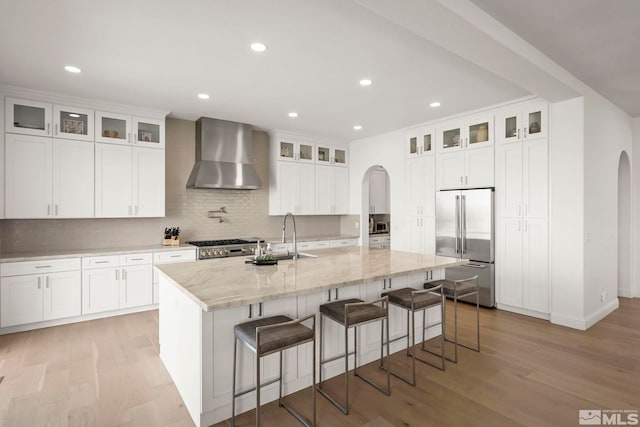 10198 Via Como, Reno, NV 89511 - kitchen featuring wall chimney range hood, arched walkways, high quality fridge, a sink, and light wood-type flooring