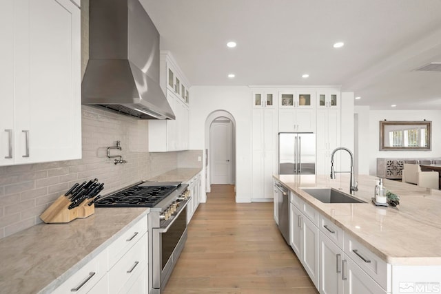 10198 Via Como, Reno, NV 89511 - kitchen featuring high quality appliances, a sink, wall chimney exhaust hood, light stone counters, and light wood-type flooring