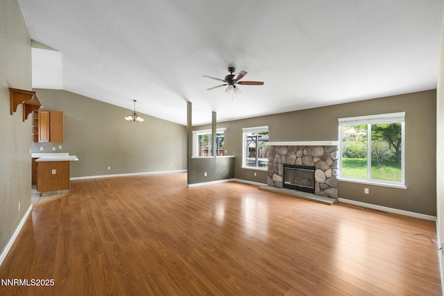 2120 Keystone Ave, Reno, NV 89503 - unfurnished living room featuring a ceiling fan, a stone fireplace, a chandelier, light wood-style flooring, and vaulted ceiling