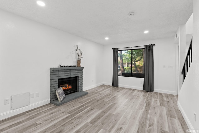 4580 Matich Dr, Reno, NV 89502 - unfurnished living room with wood finished floors, a brick fireplace, recessed lighting, a textured ceiling, and stairs