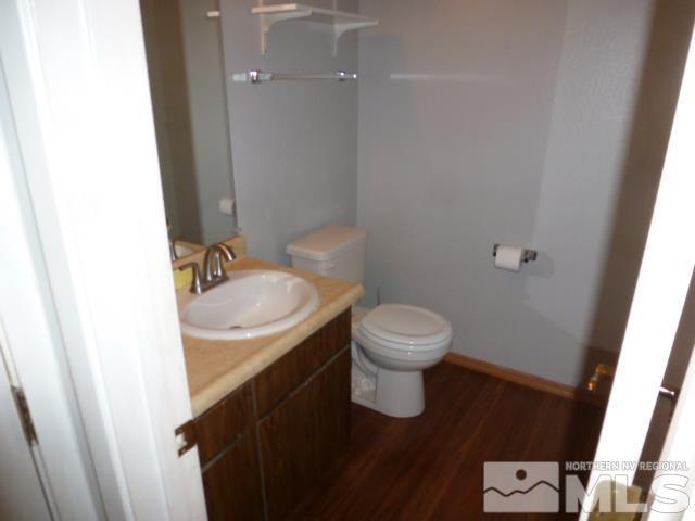 4650 Rio Poco Rd, Reno, NV 89502 - half bath featuring toilet, wood finished floors, vanity, and baseboards