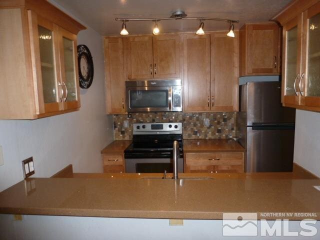 4650 Rio Poco Rd, Reno, NV 89502 - kitchen featuring stainless steel appliances, a sink, decorative backsplash, and glass insert cabinets