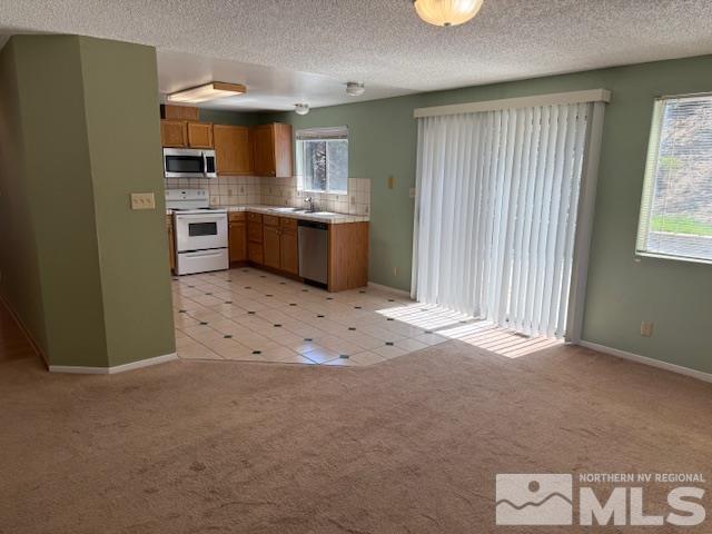 6700 Sandia Dr, Reno, NV 89523 - kitchen with stainless steel appliances, healthy amount of natural light, brown cabinets, light carpet, and a textured ceiling