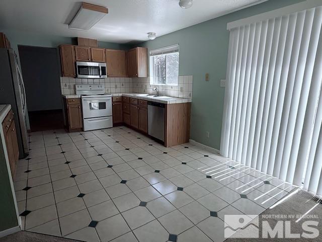 6700 Sandia Dr, Reno, NV 89523 - kitchen featuring stainless steel appliances, tasteful backsplash, light countertops, brown cabinetry, and a sink
