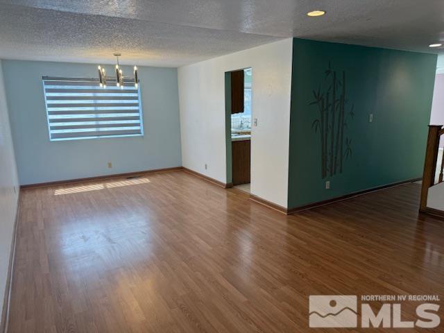 6700 Sandia Dr, Reno, NV 89523 - empty room with a chandelier, wood finished floors, baseboards, and a textured ceiling