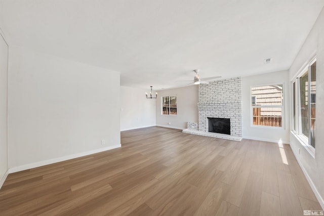 983 Melba Dr, Reno, NV 89503 - unfurnished living room featuring light wood-style floors, a ceiling fan, a chandelier, a brick fireplace, and baseboards