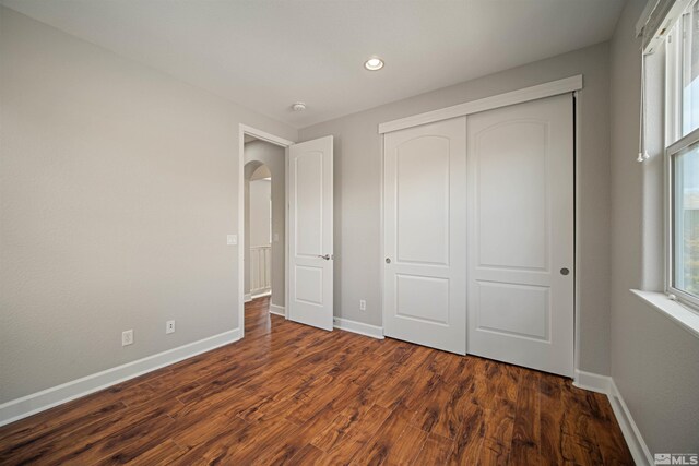 7609 Stone Bluff Way, Reno, NV 89523 - unfurnished bedroom with baseboards, arched walkways, dark wood finished floors, recessed lighting, and a closet