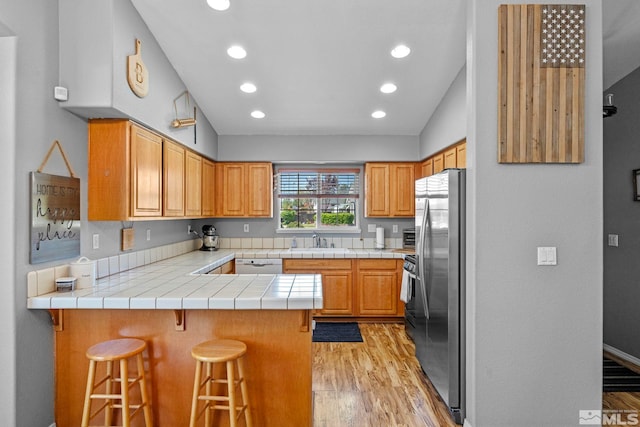1359 Whooping Crane Dr, Sparks, NV 89441 - kitchen featuring freestanding refrigerator, a peninsula, light wood-style floors, dishwasher, and vaulted ceiling