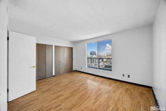 280 Island Ave Unit 1802, Reno, NV 89501 - unfurnished bedroom featuring multiple closets, wood finished floors, a textured ceiling, and baseboards