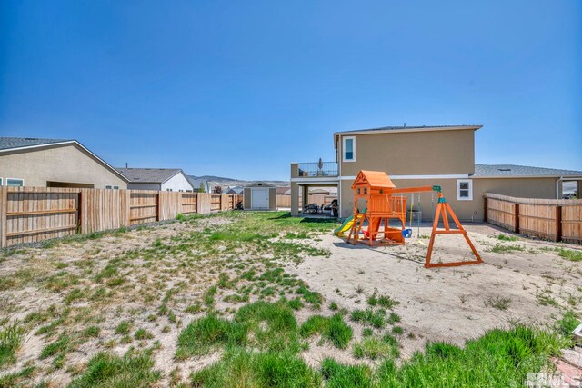7836 Tarkio Ct, Sparks, NV 89436 - rear view of house with a playground, a shed, a fenced backyard, an outbuilding, and stucco siding