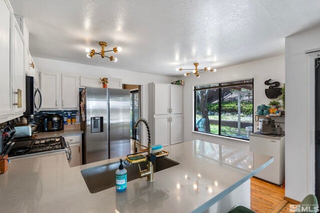 5276 Simons Dr, Reno, NV 89523 - kitchen with stainless steel appliances, a chandelier, a sink, light countertops, and a peninsula