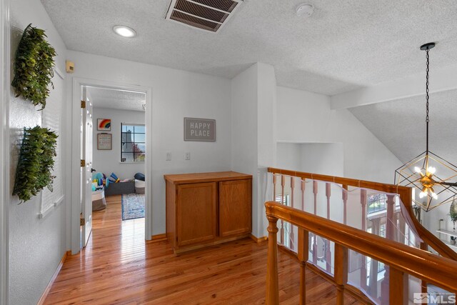 5276 Simons Dr, Reno, NV 89523 - corridor featuring an upstairs landing, a textured ceiling, a chandelier, light wood finished floors, and baseboards