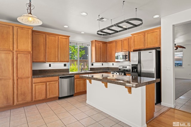 10655 Birch Point Ct, Reno, NV 89521 - kitchen with appliances with stainless steel finishes, a sink, a breakfast bar area, recessed lighting, and brown cabinetry