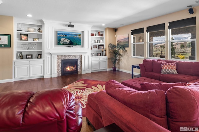living room featuring baseboards, wood-type flooring, and a tiled fireplace