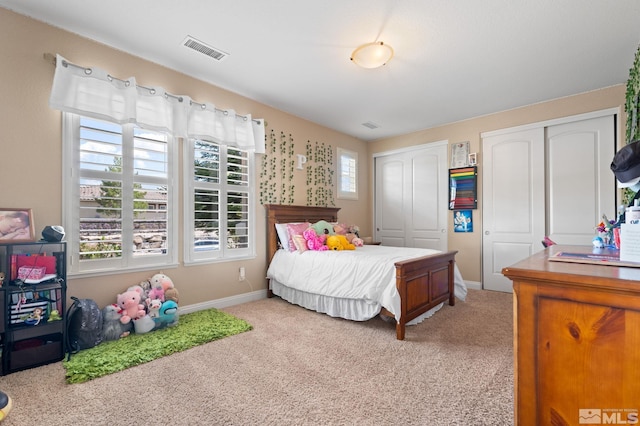 carpeted bedroom featuring multiple closets and baseboards