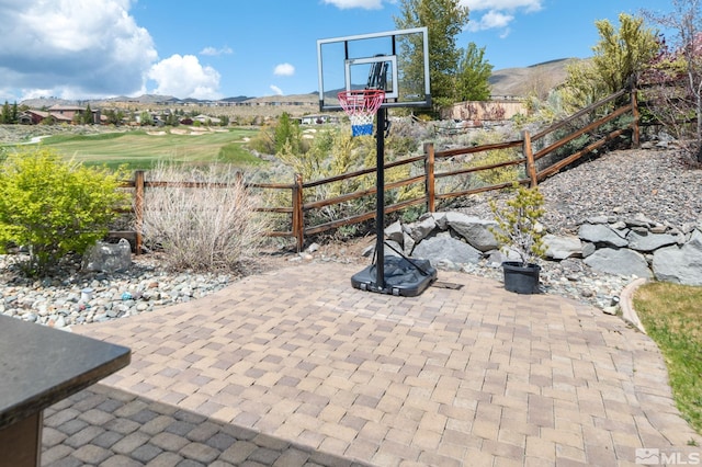 view of basketball court featuring fence and a mountain view
