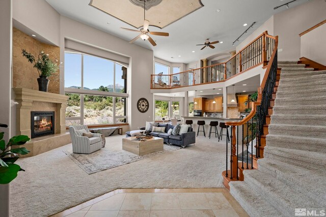 202 Paddington Ct, Reno, NV 89511 - tiled living room with carpet flooring, ceiling fan, a fireplace, stairs, and a high ceiling