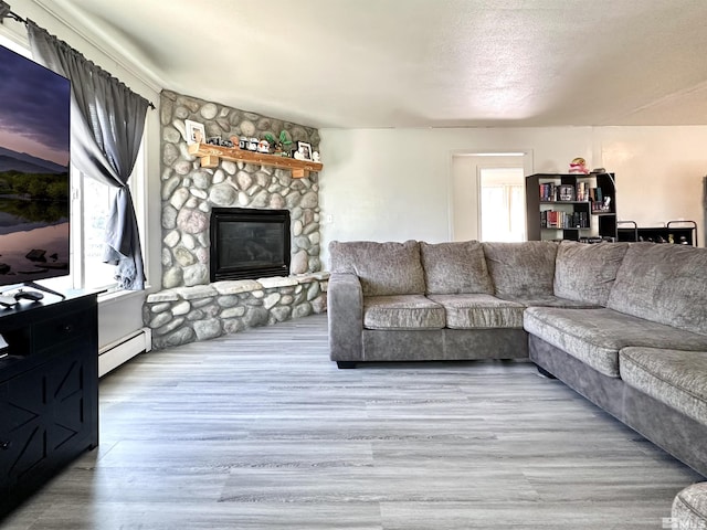 living area with a baseboard radiator, a fireplace, and wood finished floors