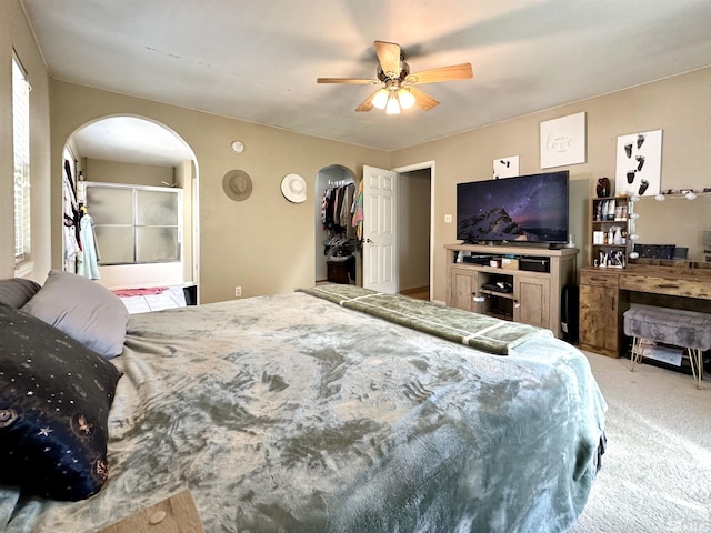 bedroom with arched walkways, light colored carpet, and ceiling fan