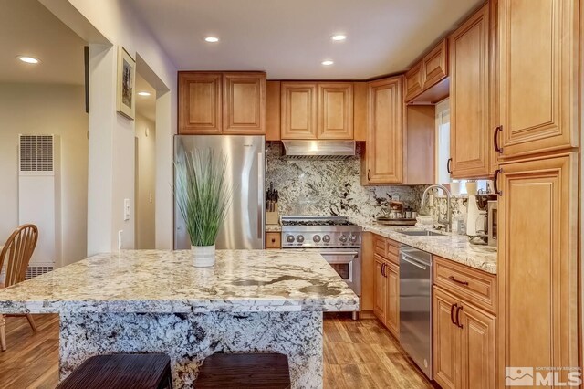 758 Milky Way Ct Unit E, Stateline, NV 89449 - kitchen featuring a heating unit, appliances with stainless steel finishes, a sink, under cabinet range hood, and light stone counters