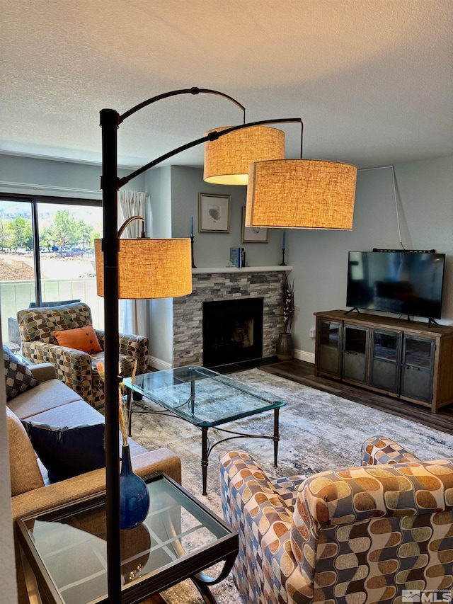 2855 Idlewild Dr Apt 124, Reno, NV 89509 - living room featuring a textured ceiling, wood finished floors, a stone fireplace, and baseboards