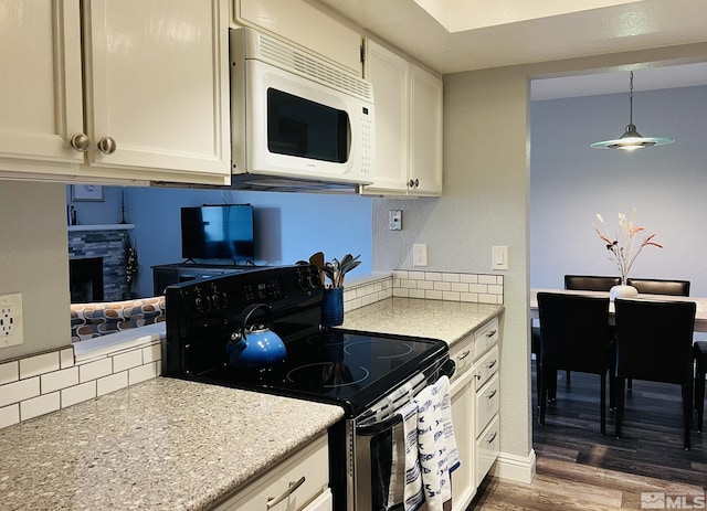 2855 Idlewild Dr Apt 124, Reno, NV 89509 - kitchen with electric range, white microwave, decorative backsplash, dark wood-style flooring, and a stone fireplace