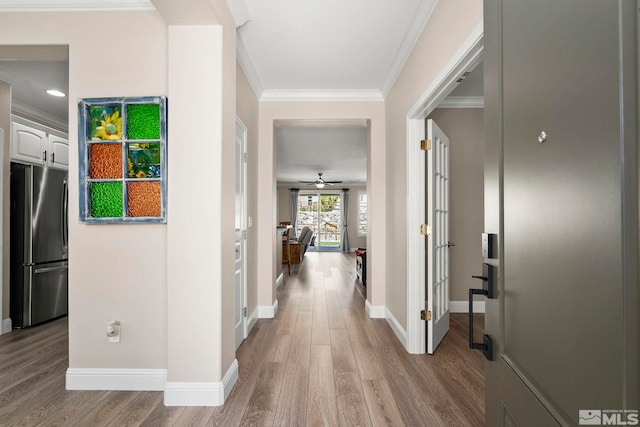 hall featuring wood finished floors, crown molding, baseboards, and french doors