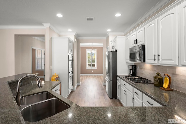 kitchen featuring a sink, stainless steel appliances, white cabinetry, ornamental molding, and decorative backsplash