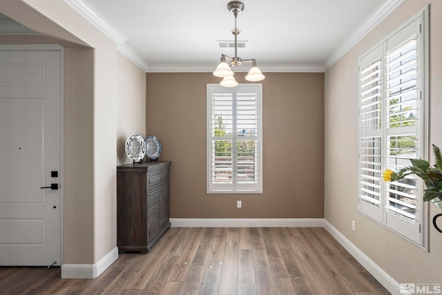 entryway with plenty of natural light, wood finished floors, a chandelier, ornamental molding, and baseboards