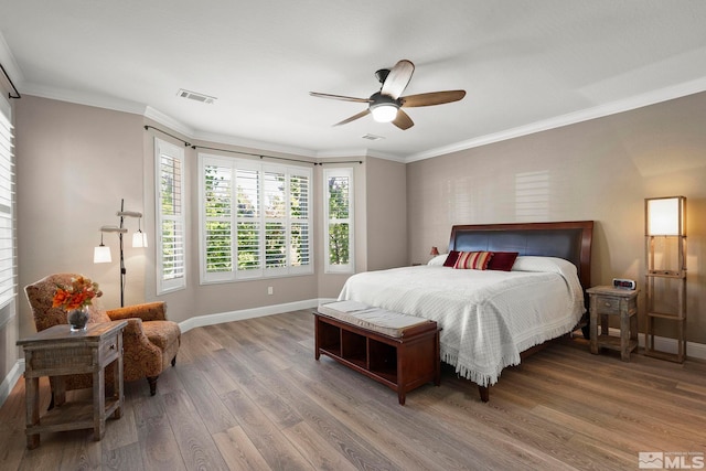 bedroom featuring baseboards, wood finished floors, ornamental molding, and a ceiling fan