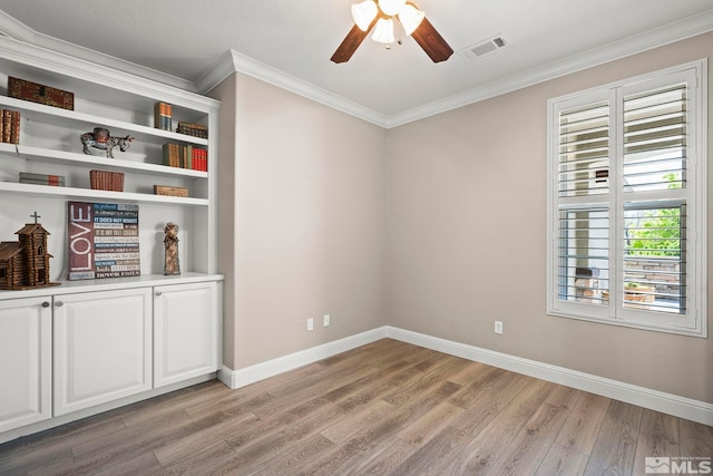 empty room featuring light wood finished floors, a ceiling fan, ornamental molding, and baseboards