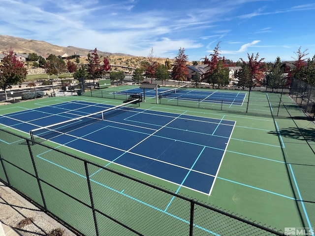view of tennis court featuring a mountain view and fence