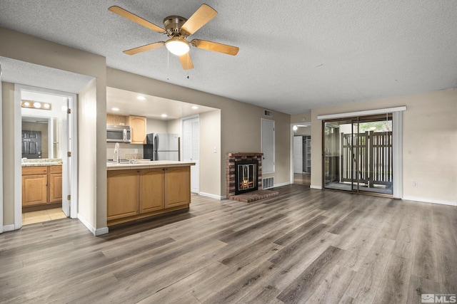 4941 Reggie Rd, Reno, NV 89502 - unfurnished living room with light wood-style floors, a textured ceiling, baseboards, a sink, and a fireplace