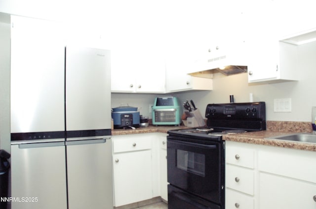 1424 E 9th Unit 2, Reno, NV 89512 - kitchen featuring black range with electric stovetop, under cabinet range hood, freestanding refrigerator, white cabinetry, and a sink