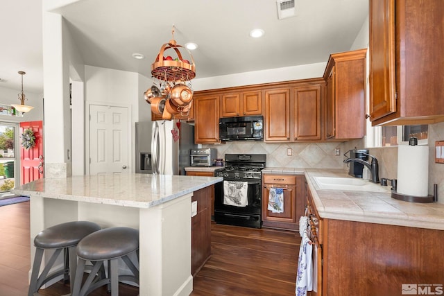 1717 Burwood Cir, Reno, NV 89521 - kitchen with black appliances, dark wood-style flooring, decorative backsplash, a breakfast bar, and brown cabinetry