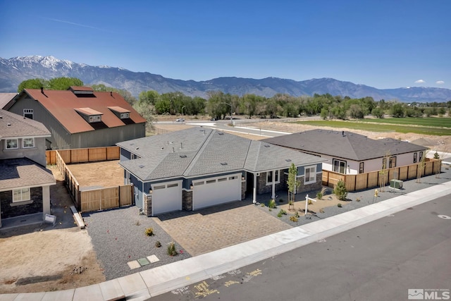 698 Sage Grouse Lp, Gardnerville, NV 89460 - view of front of house featuring an attached garage, decorative driveway, stone siding, fence, and a mountain view