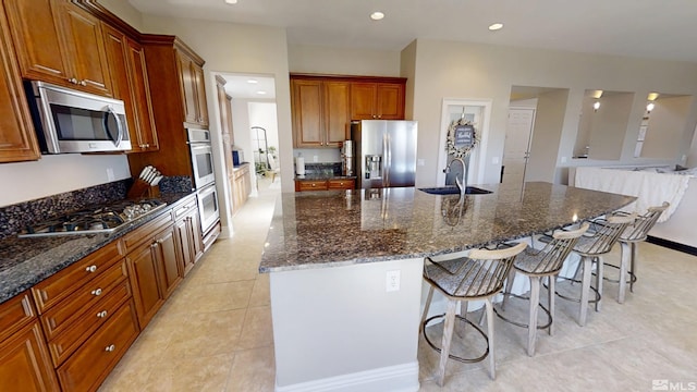 1304 Lambrusca Dr, Sparks, NV 89436 - kitchen with appliances with stainless steel finishes, a sink, a breakfast bar area, an island with sink, and dark stone counters