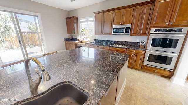 1304 Lambrusca Dr, Sparks, NV 89436 - kitchen with appliances with stainless steel finishes, dark stone countertops, brown cabinets, and light tile patterned flooring