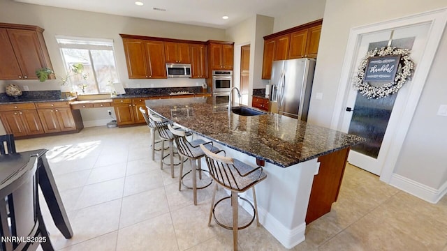 1304 Lambrusca Dr, Sparks, NV 89436 - kitchen with appliances with stainless steel finishes, a kitchen bar, light tile patterned floors, a center island with sink, and recessed lighting