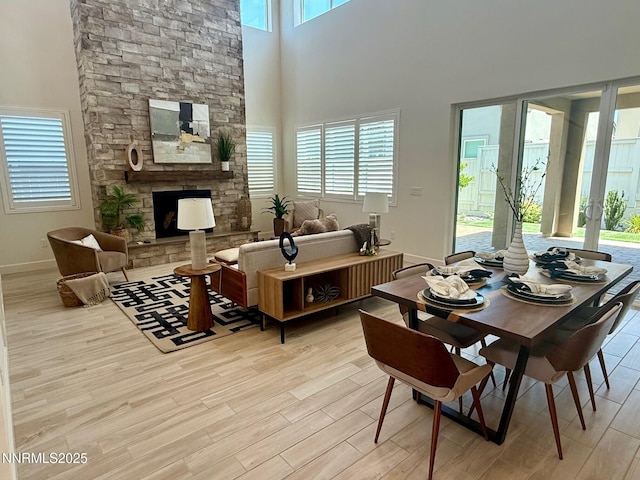 606 Braided Rope Dr, Reno, NV 89511 - dining space featuring light wood-style flooring, a fireplace, and a towering ceiling