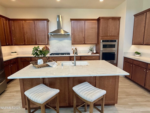 606 Braided Rope Dr, Reno, NV 89511 - kitchen with wall chimney range hood, appliances with stainless steel finishes, light stone countertops, light wood-type flooring, and a breakfast bar area