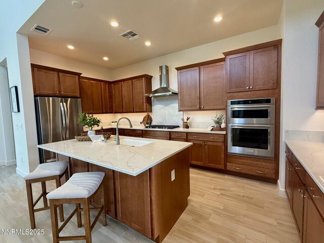 606 Braided Rope Dr, Reno, NV 89511 - kitchen with wall chimney exhaust hood, stainless steel appliances, light stone countertops, a breakfast bar, and an island with sink