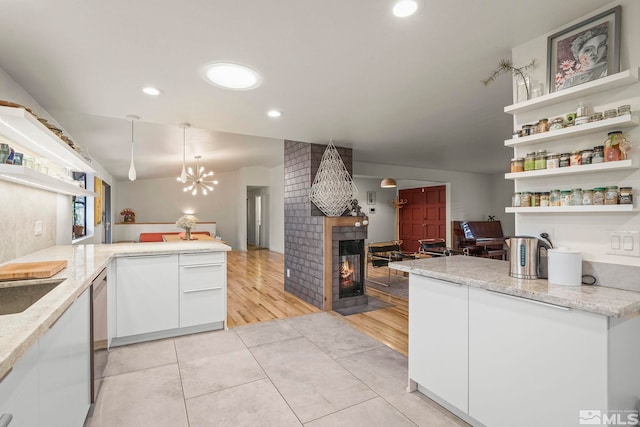 3255 Corey Dr, Reno, NV 89509 - kitchen with open shelves, a peninsula, a tiled fireplace, white cabinetry, and a chandelier
