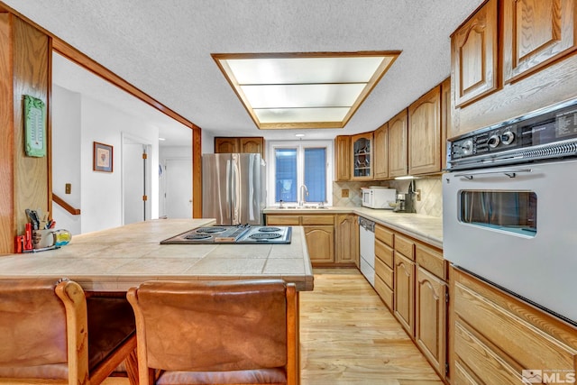 2012 Branch Ln, Reno, NV 89509 - kitchen featuring white appliances, light wood-type flooring, a kitchen breakfast bar, a textured ceiling, and backsplash