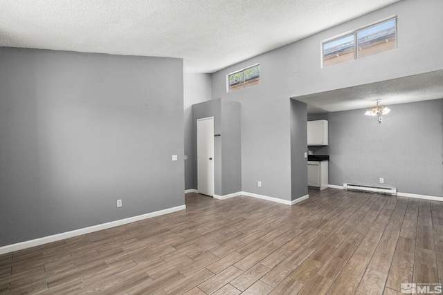 2090 Highview Ct Unit 8, Reno, NV 89512 - unfurnished living room featuring a baseboard heating unit, a towering ceiling, wood finished floors, a textured ceiling, and a chandelier