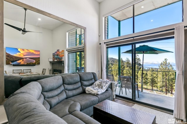 living area with a towering ceiling, wood finished floors, and ceiling fan