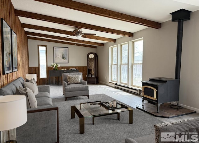 630 Wild Horse Way, Battle Mountain, NV 89820 - living room featuring a wood stove, wooden walls, a baseboard radiator, beam ceiling, and a wainscoted wall