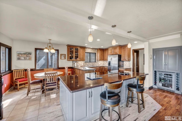 2820 Sagittarius Dr, Reno, NV 89509 - kitchen featuring stainless steel refrigerator with ice dispenser, brown cabinetry, beverage cooler, tasteful backsplash, and a spacious island